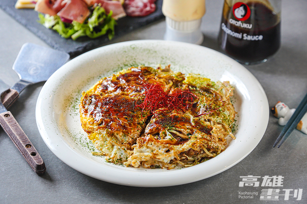 鐵板臺上依序在高麗菜、柴魚粉、特製魷魚風味天華、蔥花、豆芽菜、豬肉、麵條、雞蛋高高疊起，來一份初代廣島燒品嚐經典原味。(攝影/Carter)