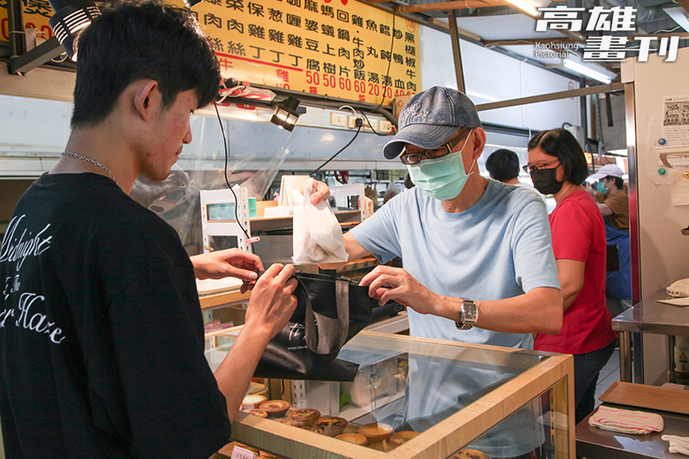 店主將熱騰騰的蛋塔仔細放入顧客自備的環保袋裡,提供美味同時減少塑膠使用。(攝影/李瑰嫻) 店主將熱騰騰的蛋塔仔細放入顧客自備的環保袋裡,提供美味同時減少塑膠使用。(攝影/李瑰嫻)