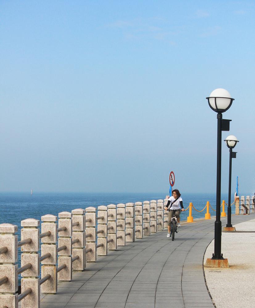 遊客在海岸公園吹海風享受悠閒步調。 遊客在海岸公園吹海風享受悠閒步調。