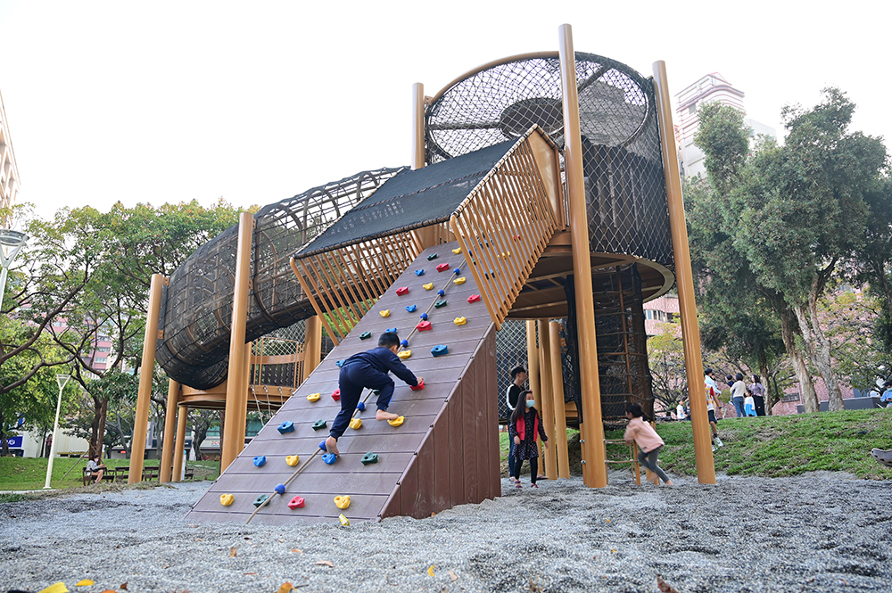 高低平台遊戲場為利用原有土丘的高低落差打造的冒險性遊樂場，平台與平台之間的連通道以各式爬網做為串連，提供孩童攀爬、抓握、登高眺遠。(圖片提供/高市府養工處)