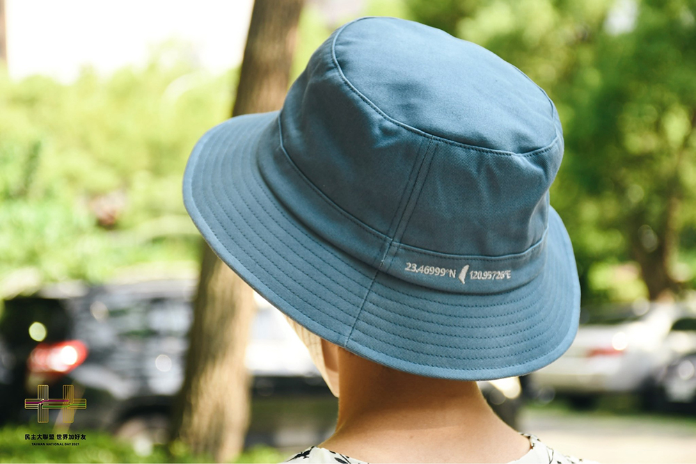 單寧色的潮流漁夫帽上面繡有緯度座標，主辦單位特別賣關子，從地圖上，可找出「第一高」的臺灣精神。(圖片提供/國慶籌備委員會)