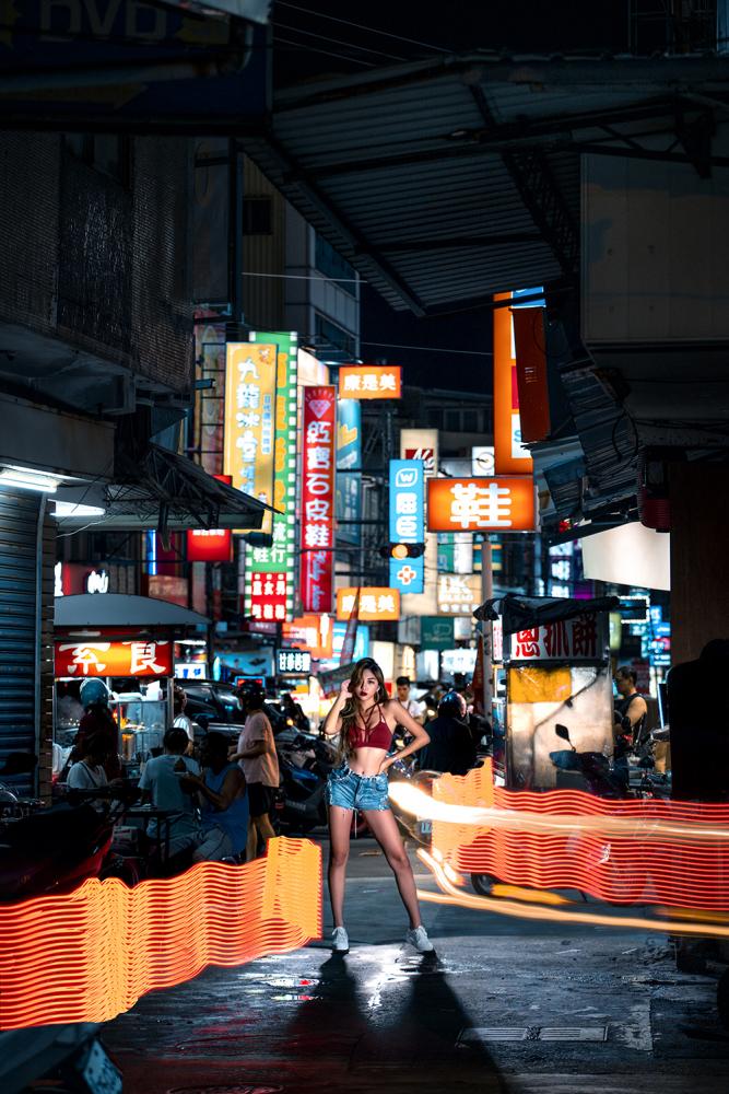 在鳳山的中山路夜市拍攝，以長鏡頭製造空間的壓縮感，招牌燈下小市民的夜生活與人物主題之間，產生高反差衝突性。(攝影/lillysixpic)(圖片提供/高市府新聞局)