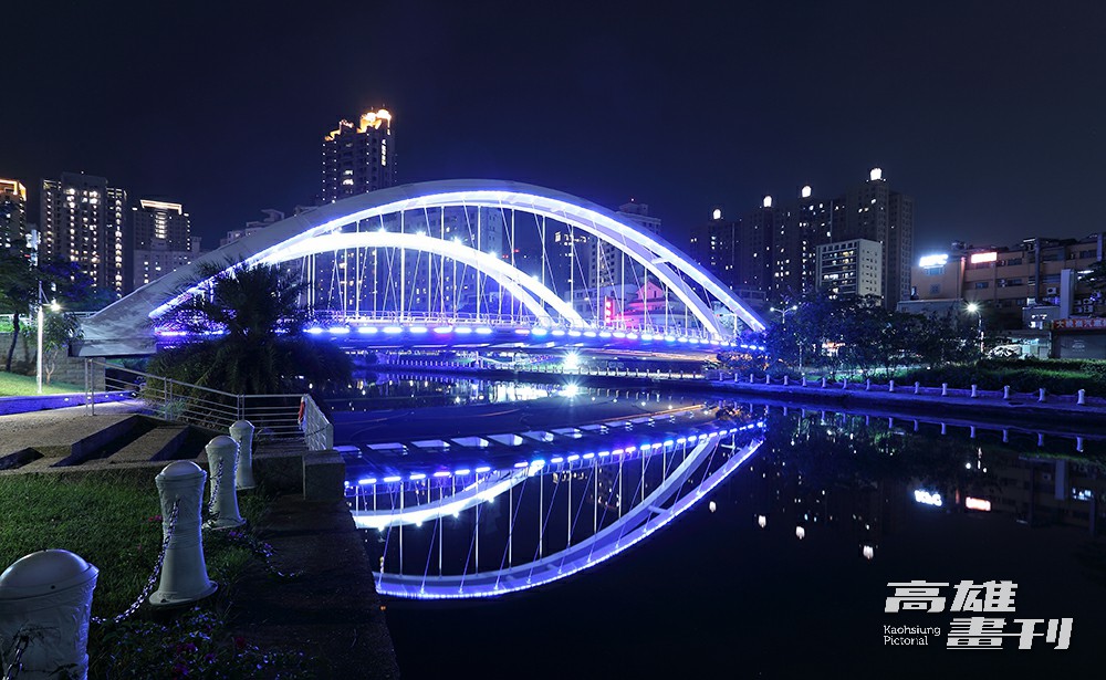 跨越愛河的願景橋位於中都濕地旁,夜晚打上藍色燈光,將河畔夜景點綴得浪漫夢幻。(攝影/Carter) 跨越愛河的願景橋位於中都濕地旁,夜晚打上藍色燈光,將河畔夜景點綴得浪漫夢幻。(攝影/Carter)